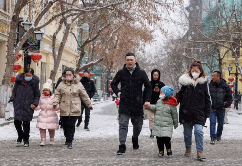 People walk with children in a pedestrian street in Harbin, Heilongjiang Province, China, February 10, 2023. REUTERS/Thomas Peter/file photo