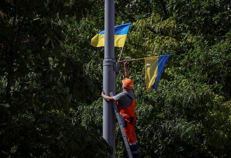 A communal worker decorates an area with national flags as part of the upcoming celebration of the Independence Day of Ukraine, amid Russia's invasion, in central Kyiv, Ukraine August 22, 2023. REUTERS/Gleb Garanich