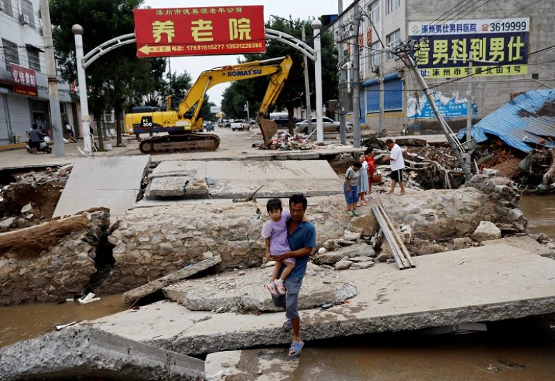 FILE PHOTO: A man holding a child walks across a damaged bridge after the rains and floods brought by remnants of Typhoon Doksuri, in Zhuozhou, Hebei province, China August 7, 2023. REUTERS/Tingshu Wang/File Photo