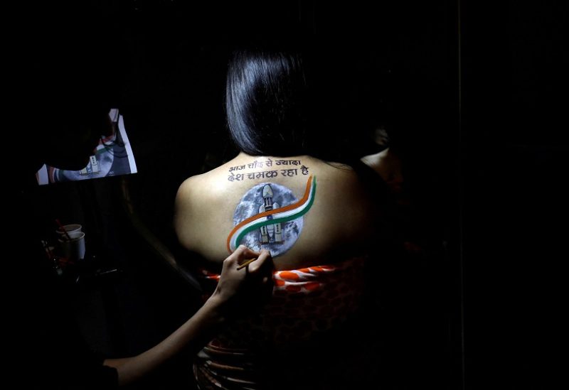 An artist applies final touches to a tattoo sketch on the back of a woman, depicting India's LVM3 M4 carrying Chandrayaan-3 spacecraft, to celebrate the landing of the spacecraft on the Moon, inside a tattoo studio in Ahmedabad, India, August 24, 2023. The words of the tattoo read: "Today the country shines more than the Moon". REUTERS/Amit Dave TPX IMAGES OF THE DAY