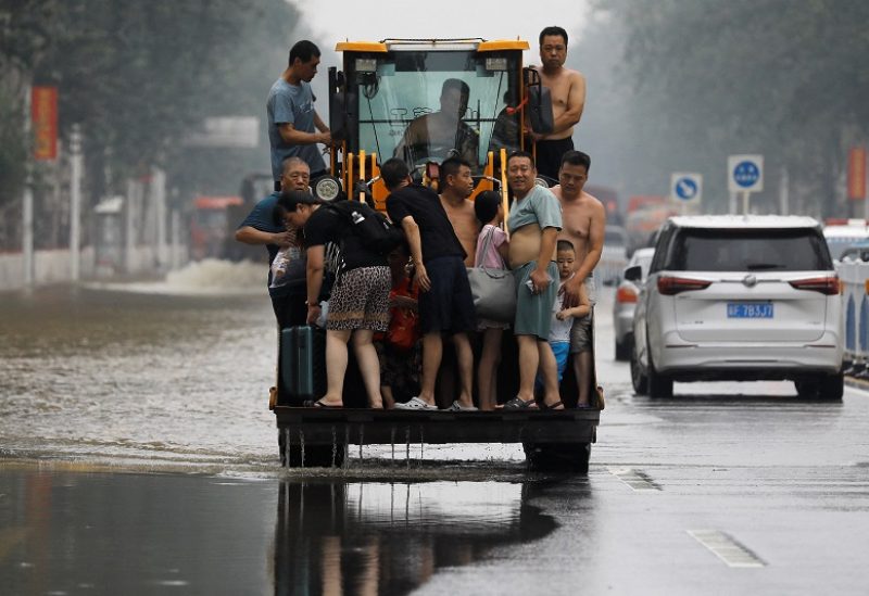 FILE PHOTO: A man operates a front loader to evacuate people through a flooded road after the rains and floods brought by remnants of Typhoon Doksuri, in Zhuozhou, Hebei province, China August 3, 2023. REUTERS/Tingshu Wang/File Photo