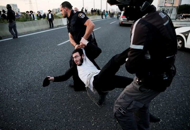 An Israeli ultra-Orthodox Jew is being carried away by police after blocking a main road in Israel during a protest against the detention of a member of his community who refuses to serve in the Israeli army, in Bnei Brak, Israel, March 12, 2018. REUTERS/Ammar Awad/File Photo