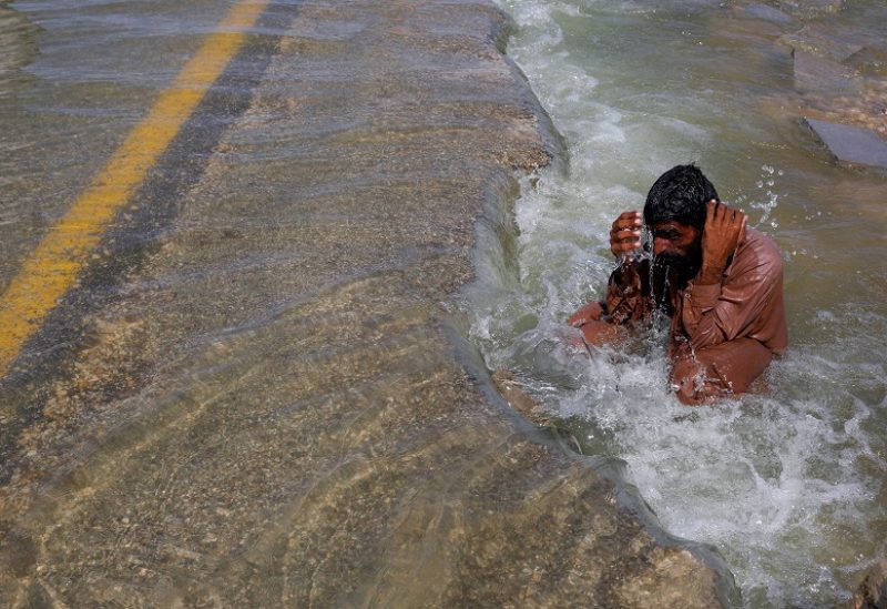 FILE PHOTO: A displaced man cools off to avoid heat on flooded highway, following rains and floods during the monsoon season in Sehwan, Pakistan, September 16, 2022. REUTERS/Akhtar Soomro TPX IMAGES OF THE DAY/File Photo