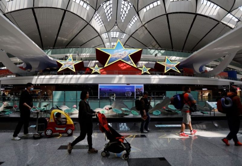 Travellers walk past an installation in the shape of five stars, at Beijing Daxing International Airport in Beijing, China April 24, 2023. REUTERS