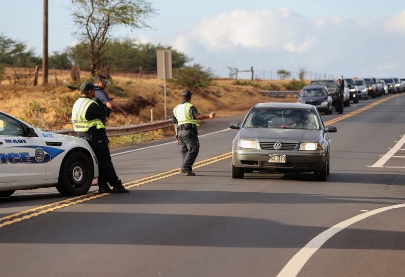 Police stop cars leading to west Maui, where wildfires destroyed much of the historic town of Lahaina, at a roadblock in Kahului, Maui, Hawaii, U.S. August 10, 2023. REUTERS/Marco Garcia
