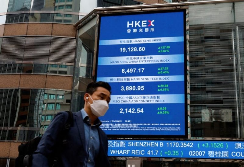 A man walks past a screen displaying the Hang Seng Index at Central district, in Hong Kong, China March 21, 2023. REUTERS/Tyrone Siu/File Photo