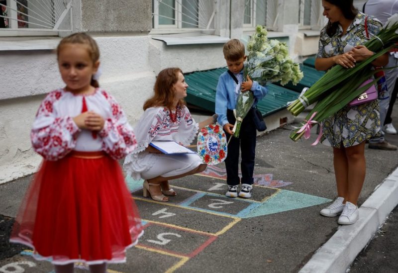 A first grader reacts as his teacher speaks with him during a ceremony to mark the start of the new school year, amid Russia's attack on Ukraine, in Kyiv, Ukraine September 1, 2023. REUTERS/Gleb Garanich