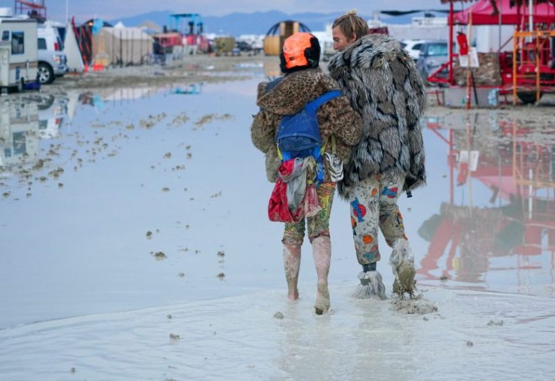 Dub Kitty and Ben Joos, of Idaho and Nevada, walk through the mud at Burning Man after a night of dancing with friends in Black Rock City, in the Nevada desert, after a rainstorm turned the site into mud September 2, 2023. Trevor Hughes/USA TODAY NETWORK via REUTERS