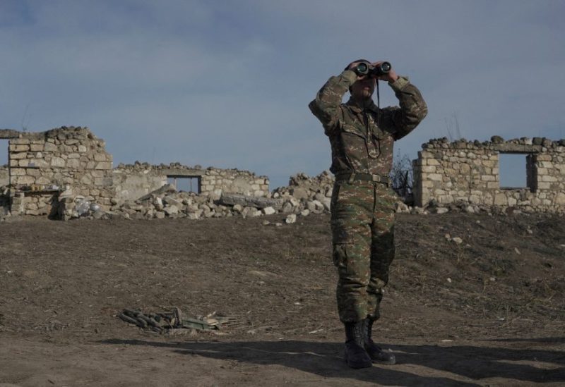 An ethnic Armenian soldier looks through binoculars as he stands at fighting positions near the village of Taghavard in the region of Nagorno-Karabakh, January 11, 2021. Picture taken January 11, 2021. REUTERS/Artem Mikryukov/File Photo