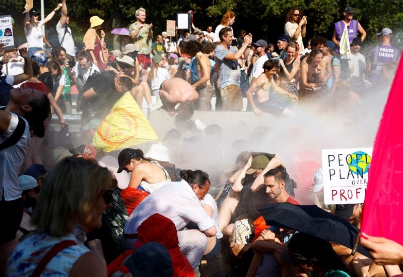 People are sprayed by a water cannon, as climate activists block the A12 highway in The Hague, Netherlands, September 9, 2023. REUTERS/Piroschka van de Wouw