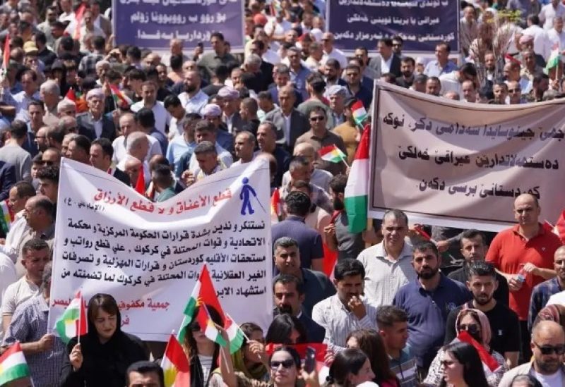 People lift banners during a rally in Dohuk city in the autonomous Kurdish region of northern Iraq on September 5, 2023, to protest unpaid salaries for civil servants for which they hold the Baghdad federal government responsible, and in support of Kurds in Kirkuk. (AFP)