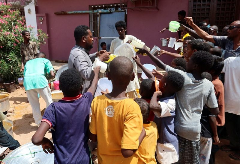 People hold pots as volunteers distribute food in Omdurman, Sudan, September 3, 2023. REUTERS/El Tayeb Siddig