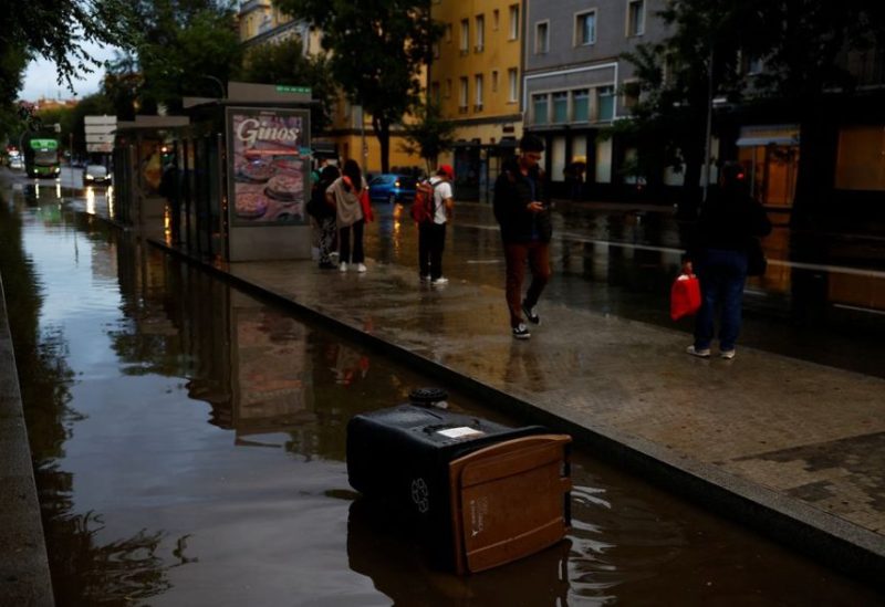 People wait for the bus by a flooded road caused by heavy rain, following a red alert for a severe storm from Spain's State Meteorological Agency (AEMET), in Madrid, Spain, September 4, 2023. REUTERS