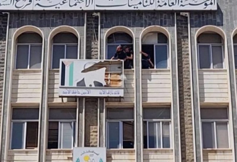 People tear down a banner with the picture of former Syrian President Hafez Al-Assad from a government building in Sweida, Syria, September 4, 2023 in this screen grab taken from a video. Suwayda 24/Handout via REUTERS