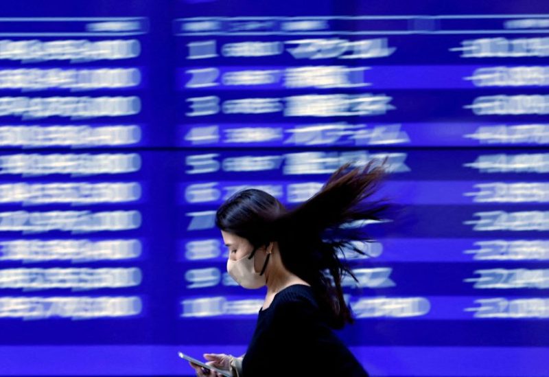A passerby walks past an electric monitor displaying recent movements of various stock prices outside a bank in Tokyo, Japan, March 22, 2023. REUTERS/Issei Kato/File Photo