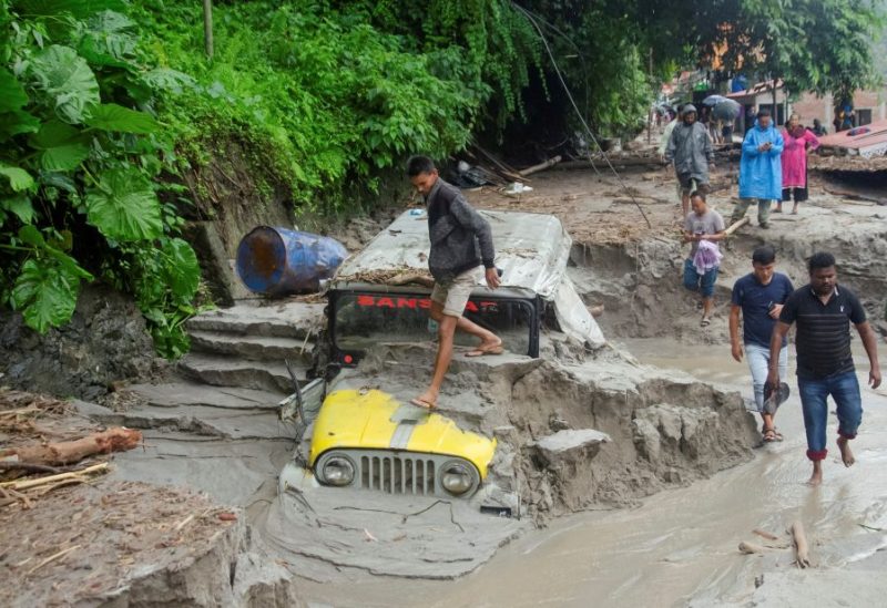 People walk along a street as a jeep is buried in the mud due to the flood at Teesta Bazaar in Kalimpong District, West Bengal, India October 4, 2023. REUTERS/Brihat Rai/File Photo