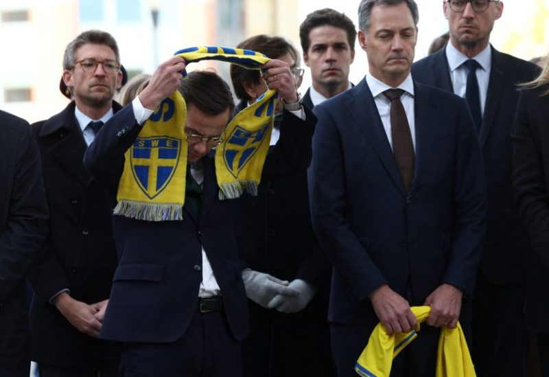Swedish Prime Minister Ulf Kristersson wears a Sweden scarf as he and Belgian Prime Minister Alexander De Croo pay tribute to the victims two days after a gunman shot dead two Swedes, at the place of the shooting in Brussels, Belgium October 18, 2023. REUTERS/Yves Herman