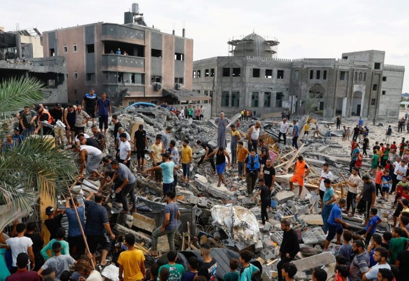 Palestinians walk among the rubble of a building destroyed in Israeli strikes, in the southern Gaza Strip October 9, 2023. REUTERS