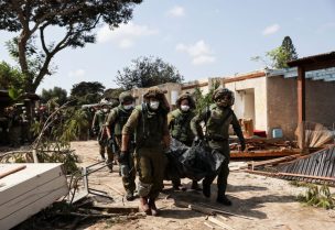 Bodies of residents and militants lie in the grounds of ravaged Israeli kibbutz