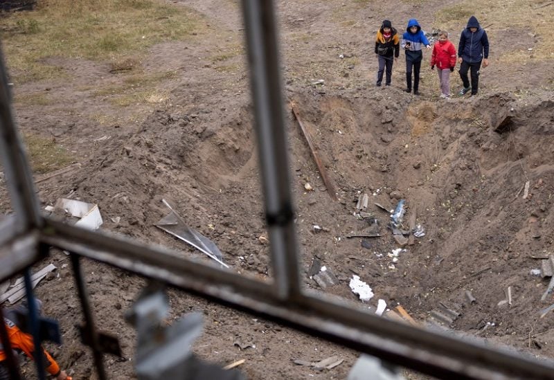 Children look at the impact crater of a Russian S-300 missile that hit next to an apartment building in Peresichne near Kharkiv, amid Russia's ongoing attack on Ukraine, October 7, 2023. REUTERS/Thomas Peter