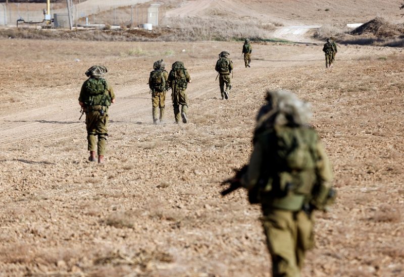 Israeli soldiers walk on grassy terrain near Israel's border with Gaza in southern Israel, October 12, 2023. REUTERS/Amir Cohen
