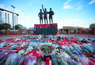 Floral tributes are pictured at the base of the “United Trinity” sculpture, depicting former Manchester United players George Best, Denis Law and Bobby Charlton, outside Old Trafford football stadium in Manchester, northwest England, on October 22, 2023, following the announcement of death of club legend Bobby Charlton on Saturday.