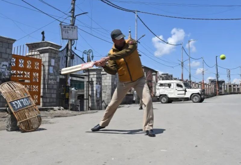An Indian police officer plays cricket on a deserted road during a strike in Srinagar