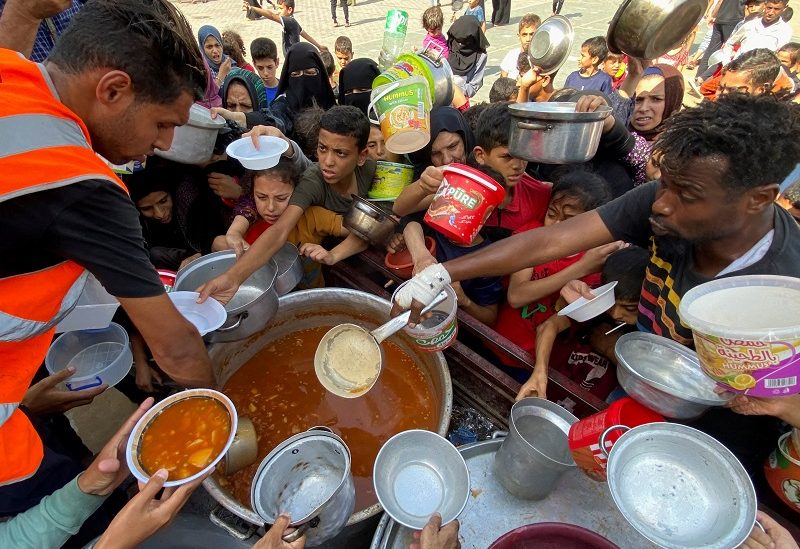 Palestinians, who fled their houses due to Israeli strikes, gather to get their share of charity food offered by volunteers, amid food shortages, at a UN-run school where they take refuge, in Rafah, in the southern Gaza Strip, October 23, 2023. REUTERS/Mahmoud al-Masri TPX IMAGES OF THE DAY