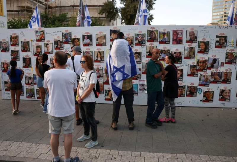 People stand next to the wall with pictures, dedicated to hostages that are being held in Gaza after they were kidnapped from Israel by Hamas gunmen on October 7, as families and supporters of hostages hold a demonstration calling for their immediate release in Tel Aviv, Israel November 3, 2023. REUTERS/Ronen Zvulun/File Photo