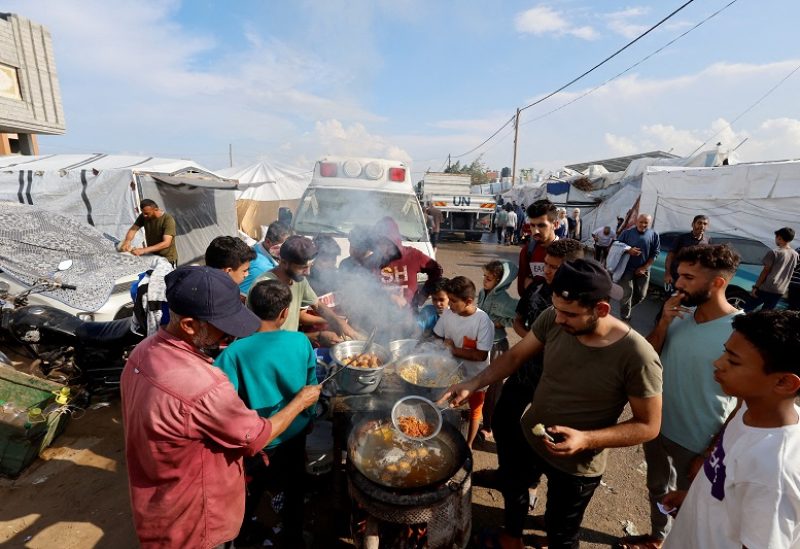 Palestinians cook food at a tent camp sheltering displaced Palestinians, amid the ongoing conflict between Israel and Palestinian Islamist group Hamas, in Khan Younis in the southern Gaza Strip, November 14, 2023. REUTERS/Mohammed Salem