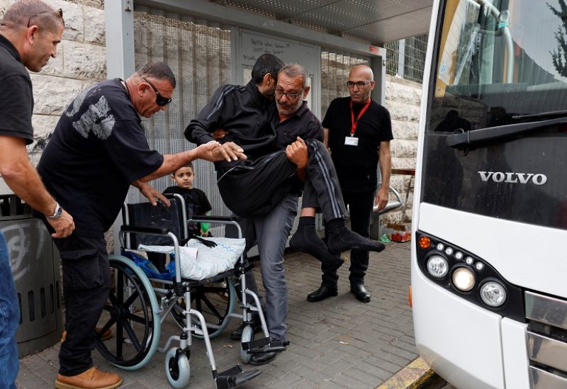 A man carries a patient as other patients from Gaza who have been receiving treatment at Makassed Hospital wait to be transported by bus to the Israeli-occupied West Bank, after they were refused permission to stay, in East Jerusalem November 13, 2023. REUTERS/James Oatway
