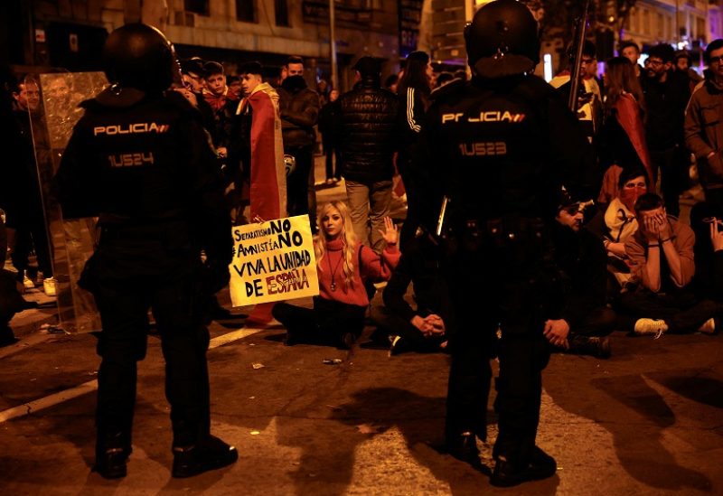 Protesters sit down in front of police officers as people demonstrate near Spain's Socialists Party (PSOE) headquarters, after Spain's socialists reached a deal with the Catalan separatist Junts party for government support, a pact which involves amnesties for people involved with Catalonia's failed 2017 independence bid, in Madrid, Spain November 18, 2023. REUTERS/Susana Ver