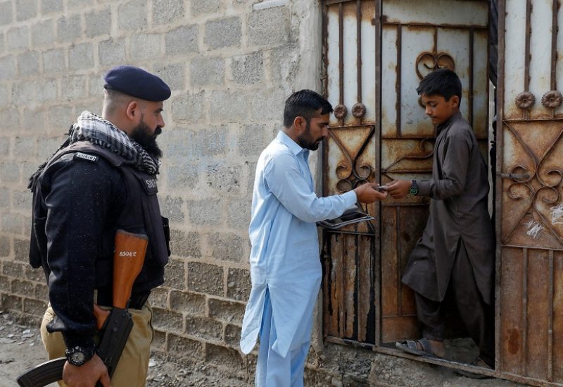 A worker from the National Database and Registration Authority (NADRA), along with a police officer, verifies the identity cards of an Afghan citizen on an online tab, during a door-to-door search and verification drive for undocumented Afghan nationals, in Afghan Camp on the outskirts of Karachi, Pakistan, November 21, 2023. REUTERS/Akhtar Soomro
