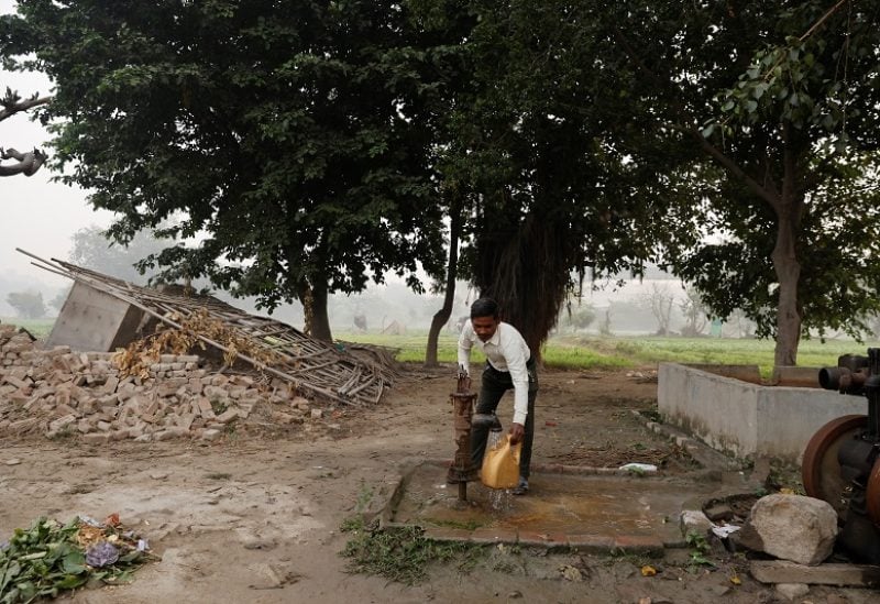 Totaram Maurya,45, a construction worker, fills water in a container using a handpump near his house on the Yamuna floodplains on a smoggy morning in New Delhi, India, November 9, 2023. REUTERS/Anushree Fadnavis
