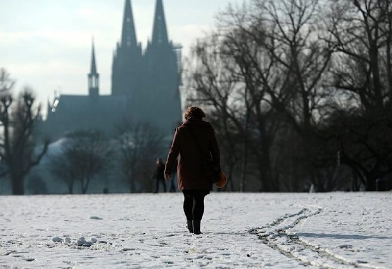 A woman walks through a park covered with snow nearby the Cologne Cathedral amid the spread of the coronavirus disease (COVID-19) in Cologne, Germany, January 24, 2021. REUTERS/Thilo Schmuelgen/ File photo