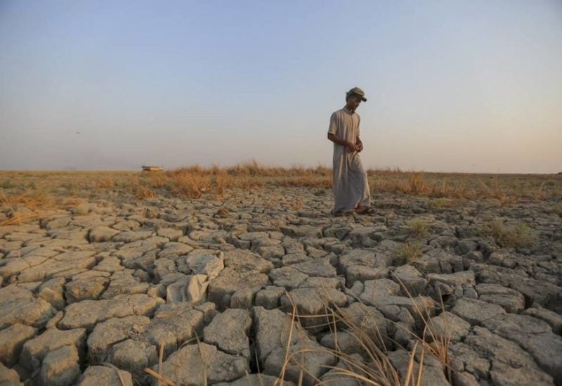 A fisherman walks across a dry patch of land in the marshes in Dhi Qar province, Iraq, Sept. 2, 2022. (AP)