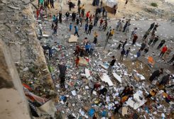 People walk among debris at the site of an Israeli strike on the apartment building, amid the ongoing conflict between Israel and Palestinian group Hamas, in Khan Younis in the southern Gaza Strip November 18, 2023.
