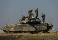 Israeli soldiers work on a tank near the border with Gaza, amid the ongoing conflict between Israel and the Palestinian Islamist group Hamas, as seen from southern Israel, December 3, 2023. Picture taken through a window. REUTERS/Alexander Ermochenko