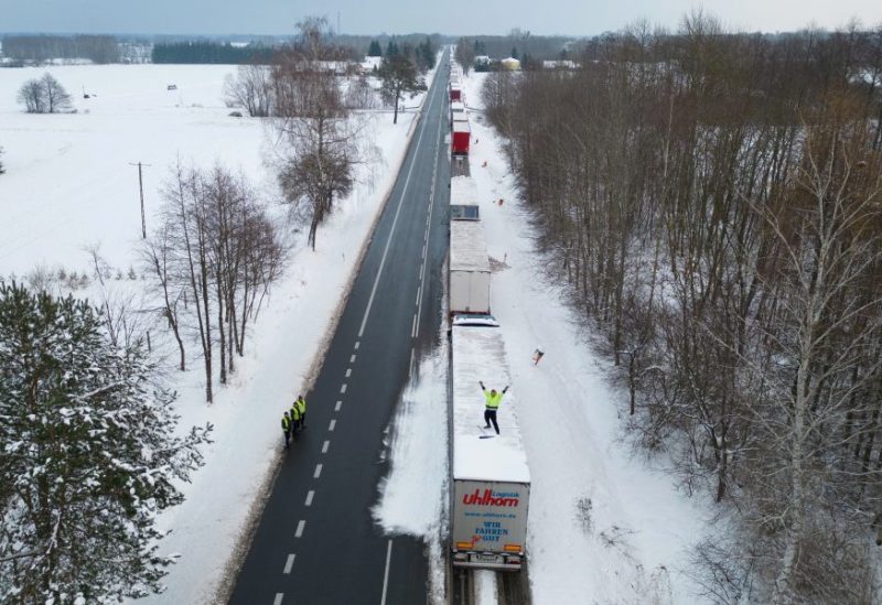 A truck driver from Ukraine waves from his truck roof while waiting in a long queue to cross the Polish-Ukrainian border at the Dorohusk-Jagodzin crossing, in Okopy, Poland, December 4, 2023. REUTERS/Kuba Stezycki/File Photo