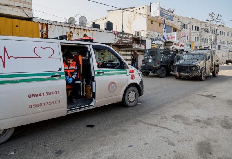An emergency worker sits in an ambulance blocked by Israeli military vehicles during a raid, amid the ongoing conflict between Israel and the Palestinian Islamist group Hamas, in Jenin, in the Israeli-occupied West Bank, December 12, 2023. REUTERS/Raneen Sawafta