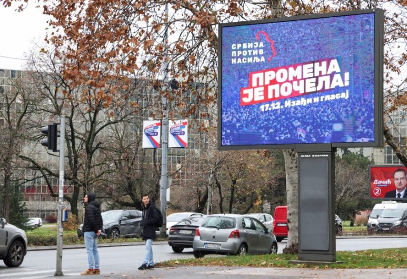 People stand next to a pre-election billboard of the opposition coalition 'Serbia Against Violence' in Belgrade, Serbia, December 14, 2023. REUTERS/Zorana Jevtic/File Photo