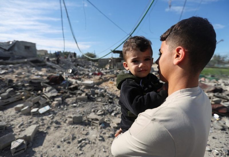 A Palestinian holds a child as they look on at the site of an Israeli strike on a house, amid the ongoing conflict between Israel and the Palestinian Islamist group Hamas, in Rafah, in the southern Gaza Strip, December 16, 2023. REUTERS/Ibraheem Abu Mustafa