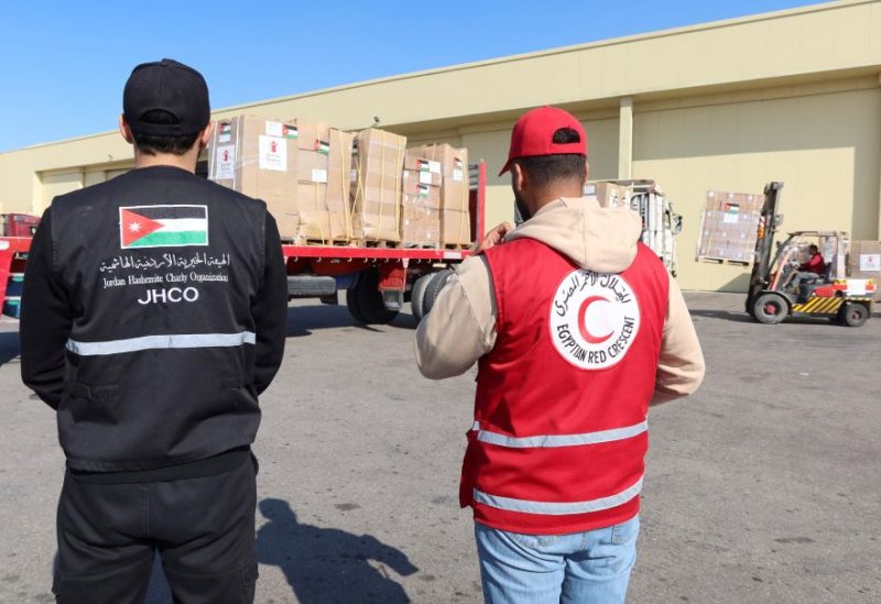 A member of Jordan Hashemite Charity Organization and Egyptian Red Crescent stand near boxes of Humanitarian aid arrived from Jordan and destined for the Gaza Strip at Al Arish airport, in Al Arish, Egypt December 19, 2023. REUTERS/Jehad Shelbak