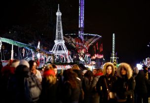 People walk in front of an illuminated Eiffel tower at a Christmas fair installed inside the Jardin des Tuileries in Paris, France, December 18, 2023. REUTERS/Sarah Meyssonnier/File Photo