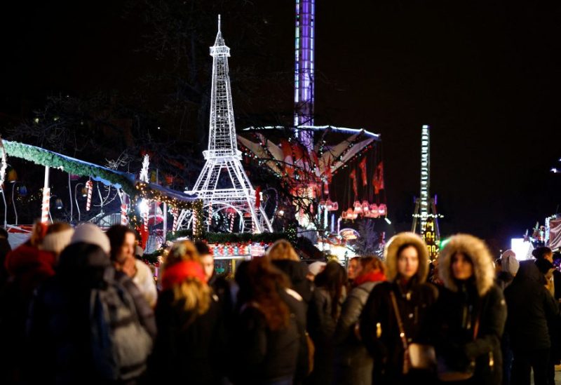 People walk in front of an illuminated Eiffel tower at a Christmas fair installed inside the Jardin des Tuileries in Paris, France, December 18, 2023. REUTERS/Sarah Meyssonnier/File Photo