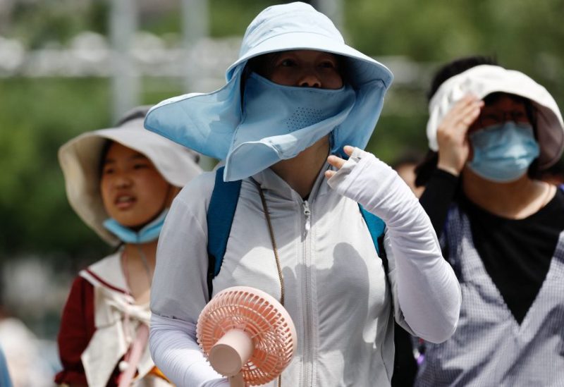 People wearing sun protection gear amid a heatwave walk on a street in Beijing, China July 1, 2023. REUTERS/Tingshu Wang/ File photo