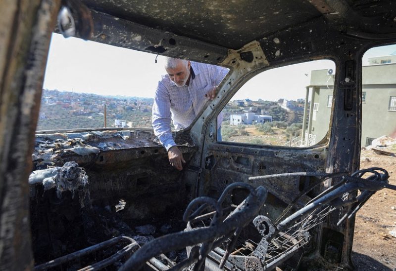 FILE PHOTO: A Palestinian checks a car burned in Israeli settlers raid near Salfit in the Israeli-occupied West Bank December 3, 2023. REUTERS/Yosri Aljamal//File Photo
