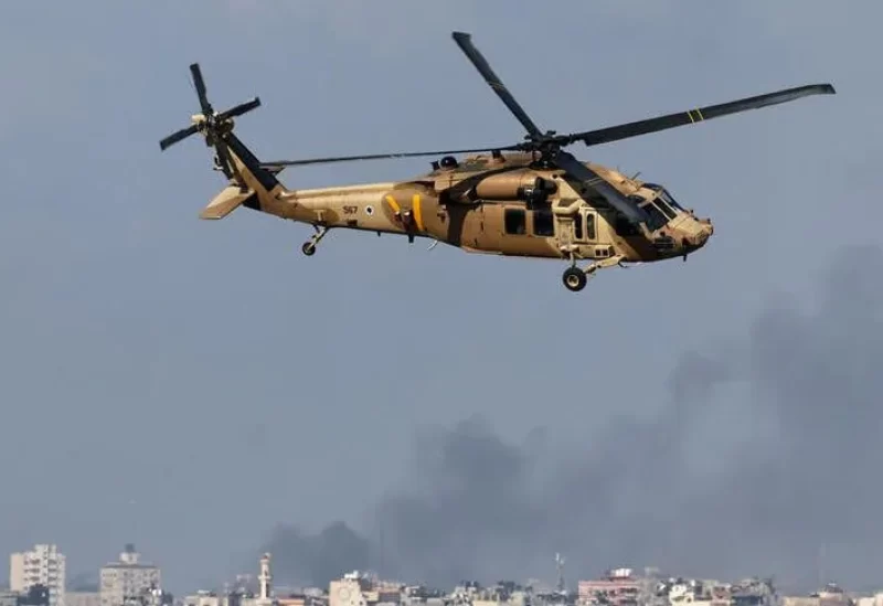 An Israeli military helicopter flies as smoke rises over Gaza, amid the ongoing conflict between Israel and the Palestinian Islamist group Hamas, as seen from southern Israel, December 6, 2023. REUTERS
